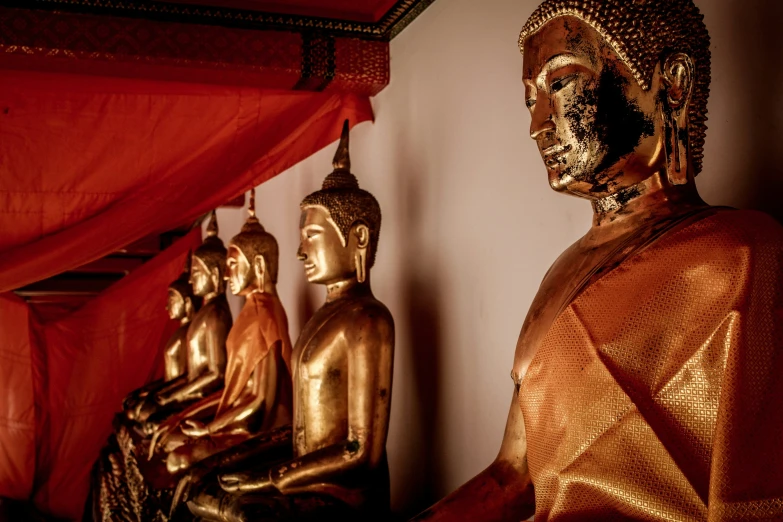 a row of buddhas, with an red curtain behind them