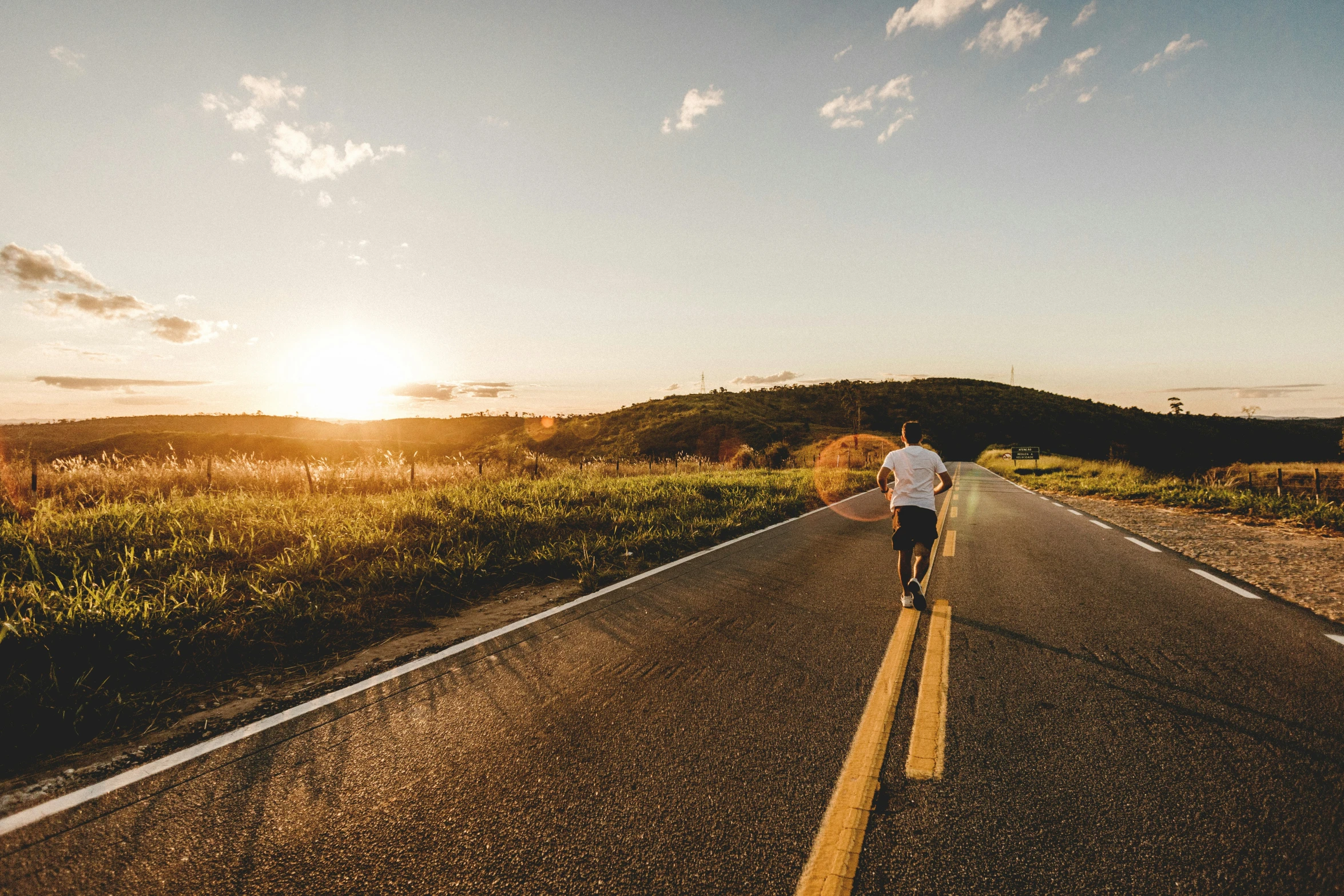 a man riding his bicycle down the middle of a road at sunset