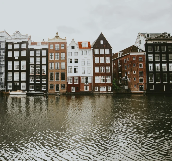 several buildings in various colors are reflecting on the water