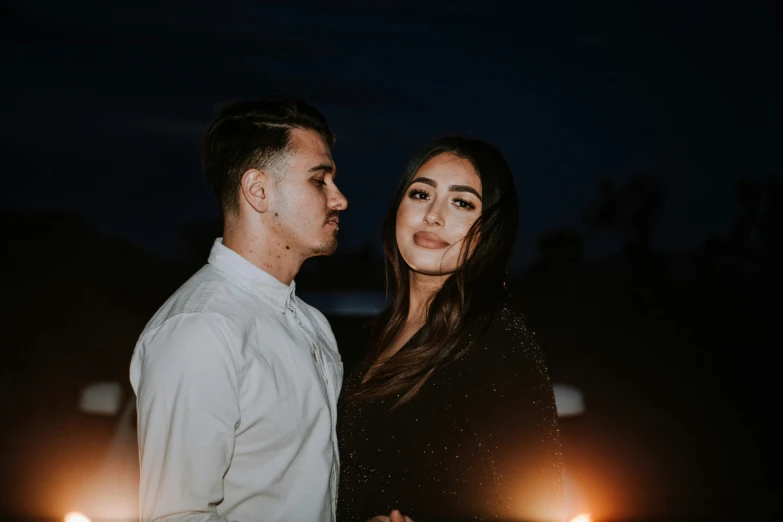 a man and woman posing together in front of some candles