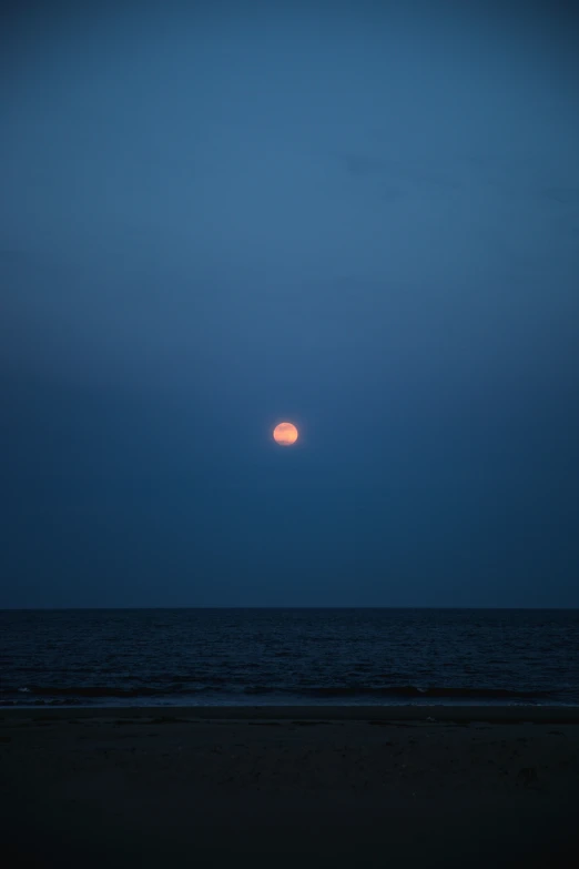 the sun is setting over the ocean in front of an object