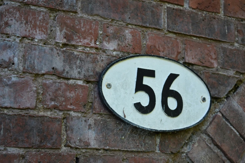 a close up of the number 56 on a brick wall