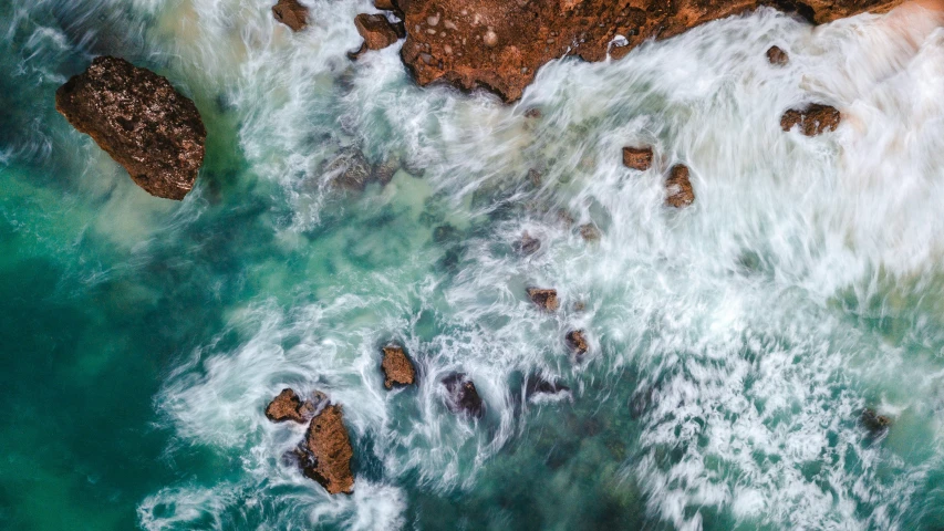 aerial view of ocean waves breaking over rocks