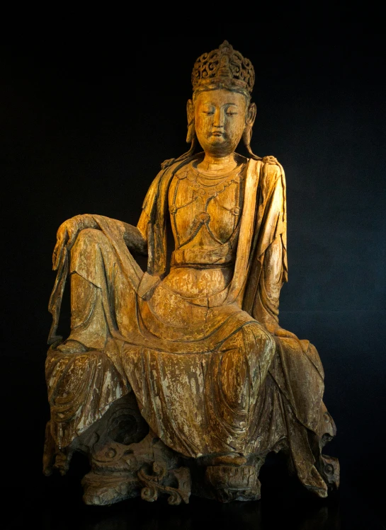 a golden buddha statue sits on top of a wooden bench