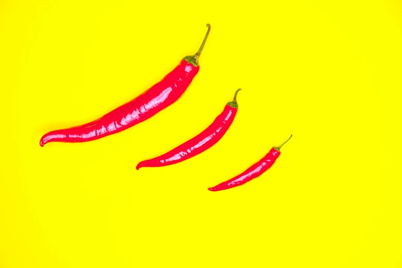 three  peppers are sitting side by side on a yellow background