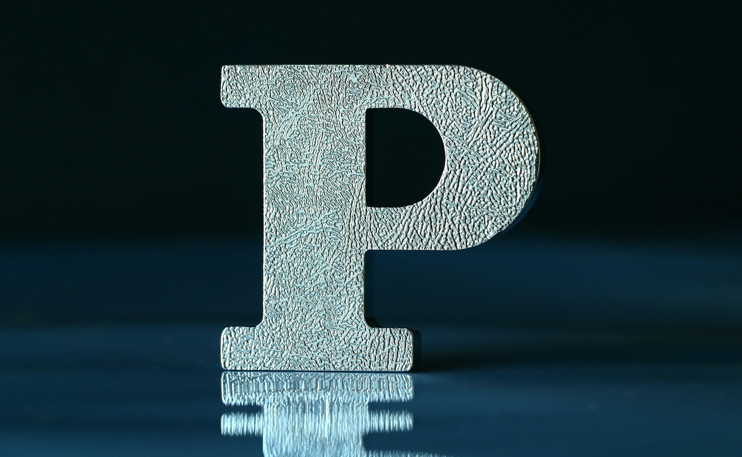 a metallic letter p that is surrounded by lots of dots
