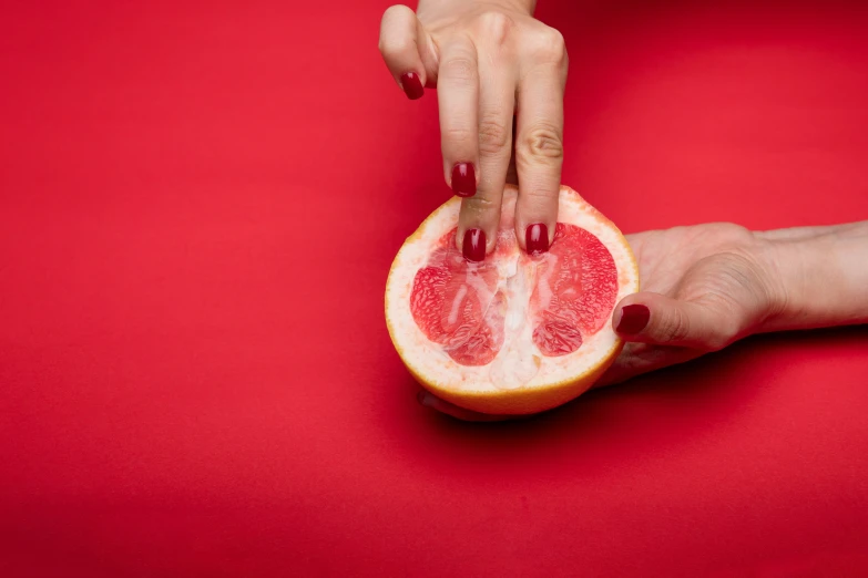 a woman's hand reaches through to grab a piece of gfruit from the other hand