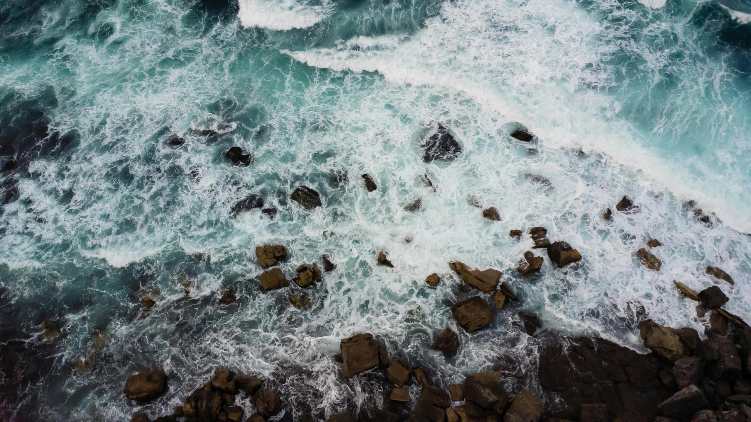 an aerial view of the ocean with rocks and water