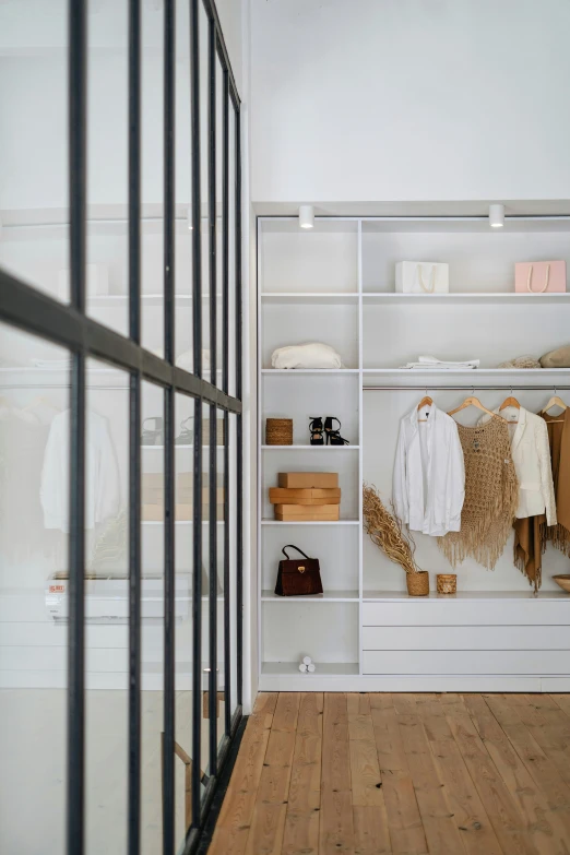 a small room with a wood floor, shelves and clothes