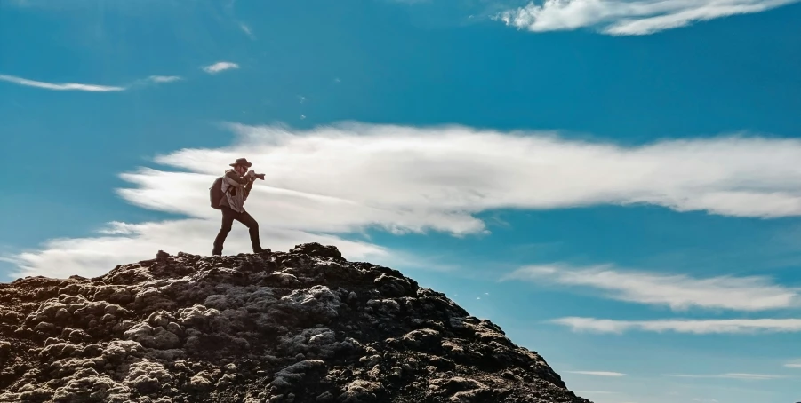 the man is standing on top of the rocky hill