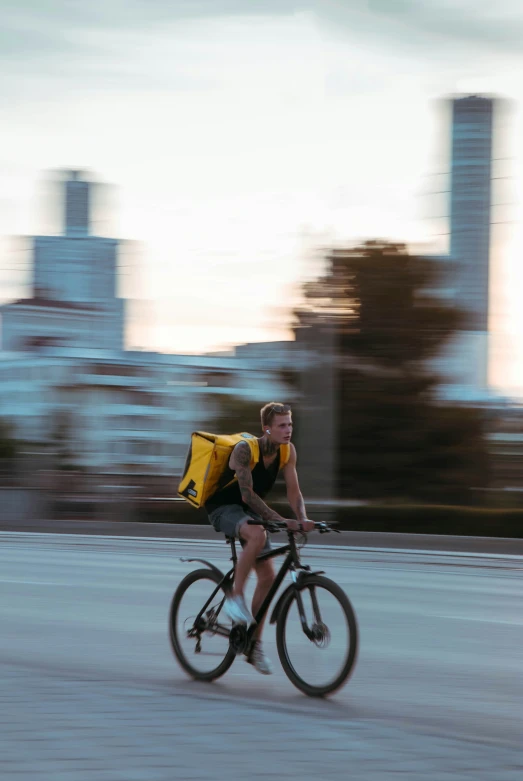 a guy riding his bike down the street in the daytime