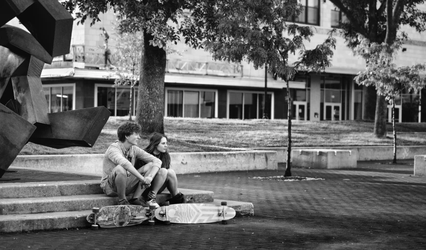 two young men are sitting on a step next to a skateboard