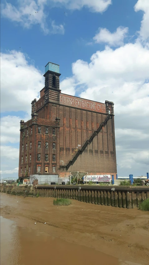 large brick building near the ocean with water below