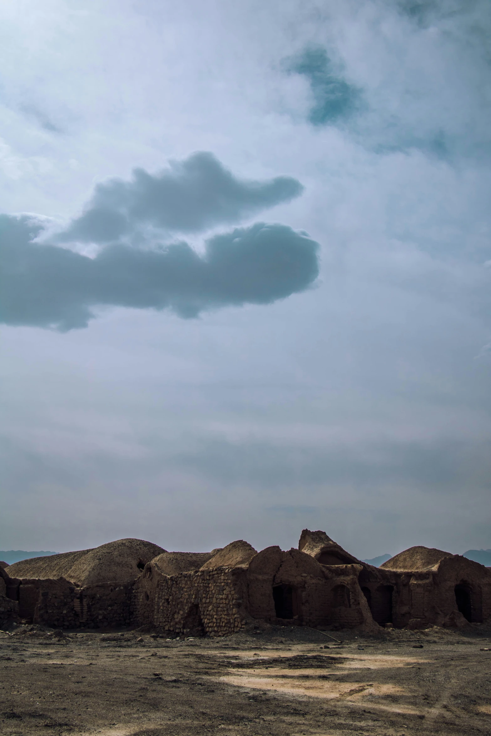 some rocks and a horse under a cloud filled sky