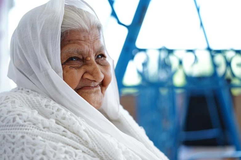 an elderly woman in white cloths is smiling