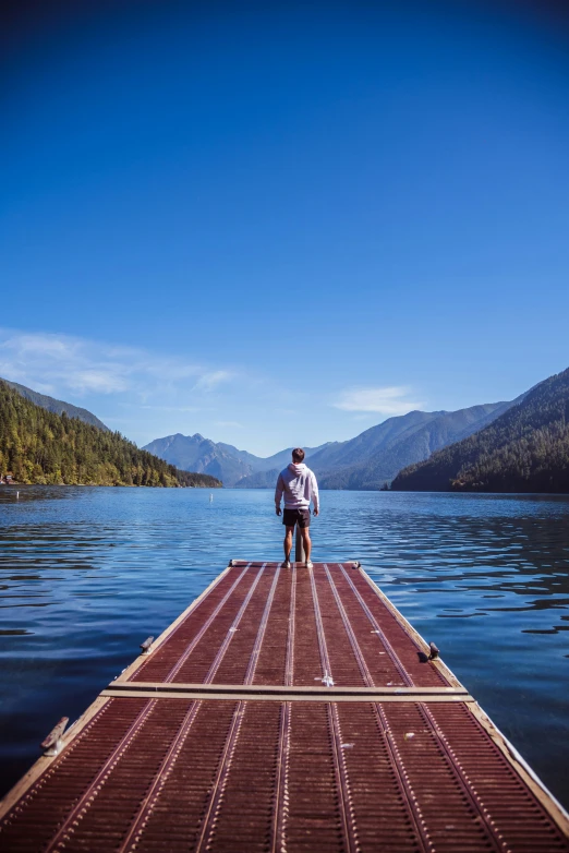 a man stands on a raft that extends out into a lake