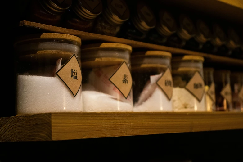 several jars with labels lined up on a shelf