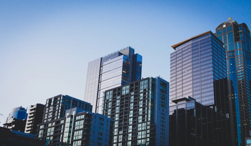 many tall buildings sit near each other against a blue sky