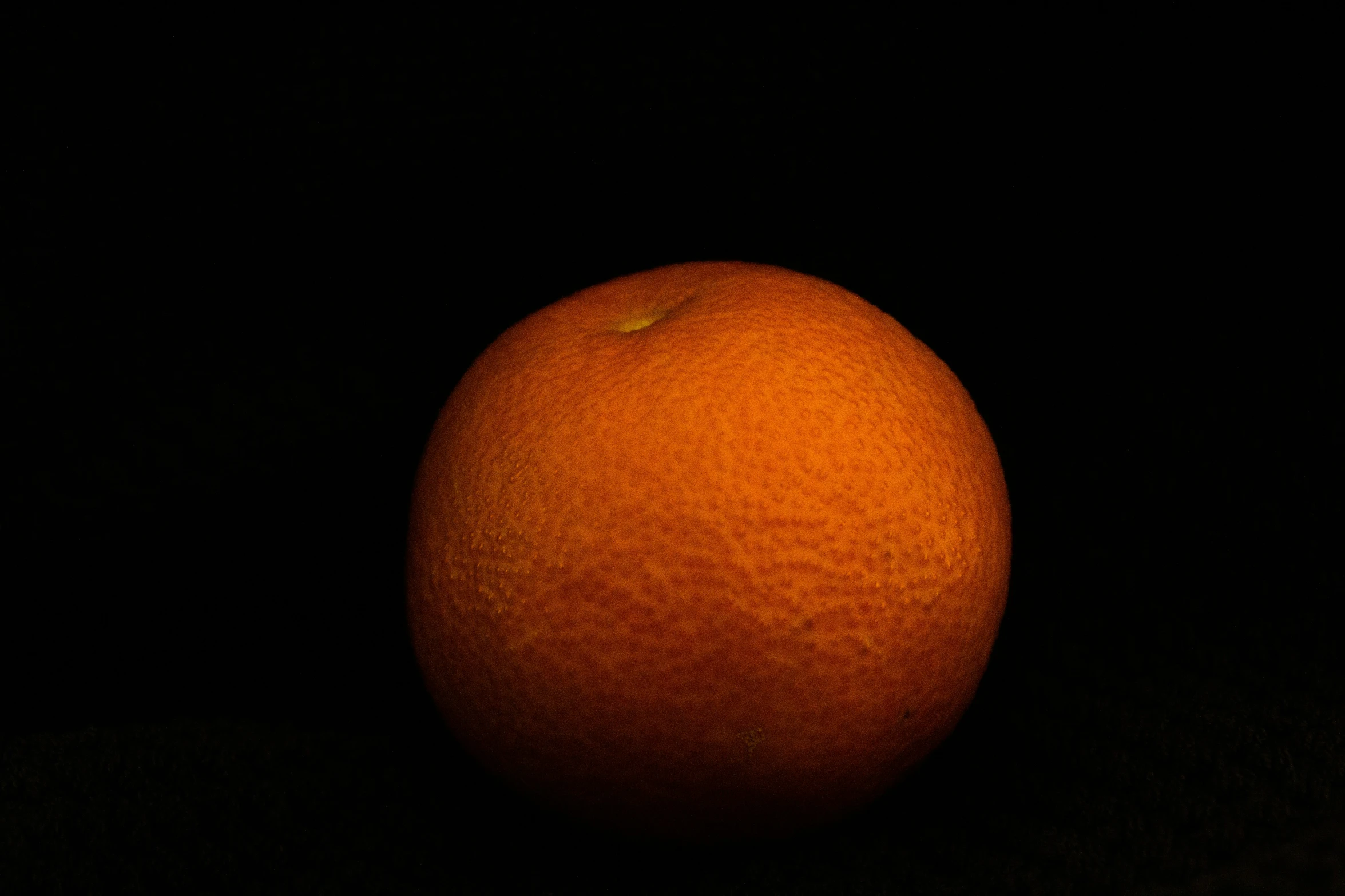 there is an orange on the table under the dark sky