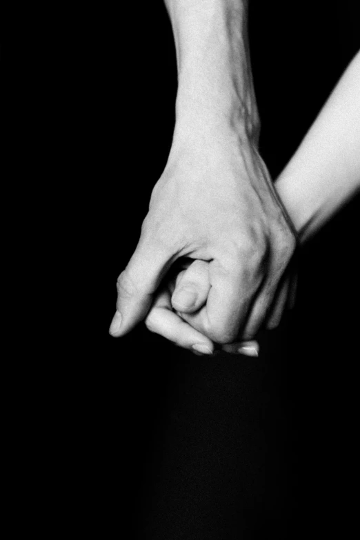 two people holding hands on a black background