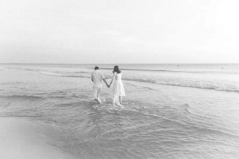 two women walking out of the ocean holding hands