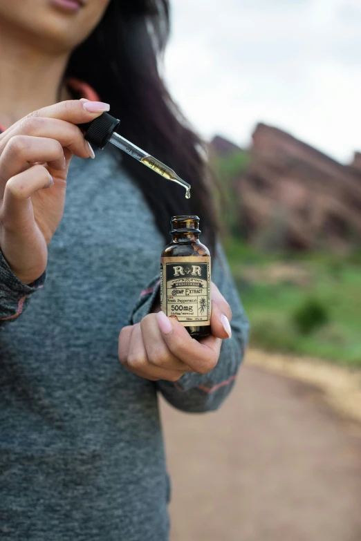 a woman holding up a bottle of brown liquid