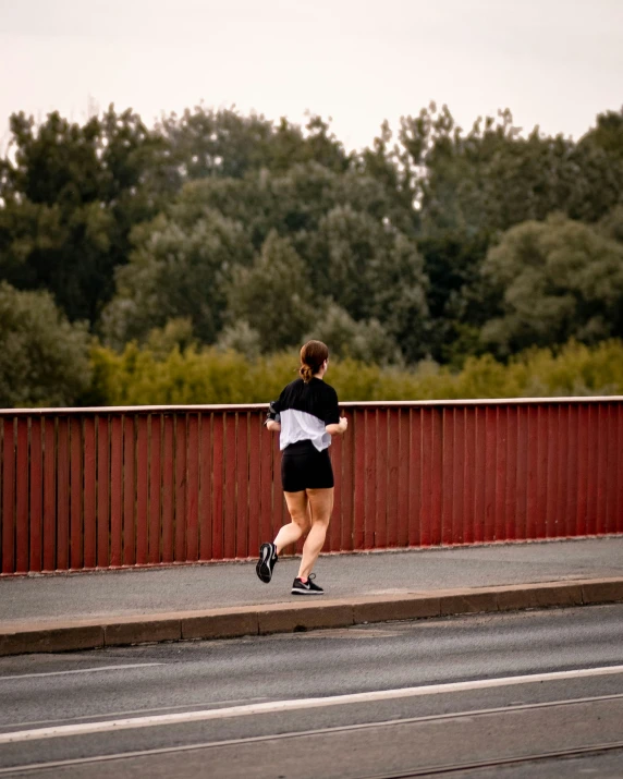 a woman wearing black shorts runs across the street
