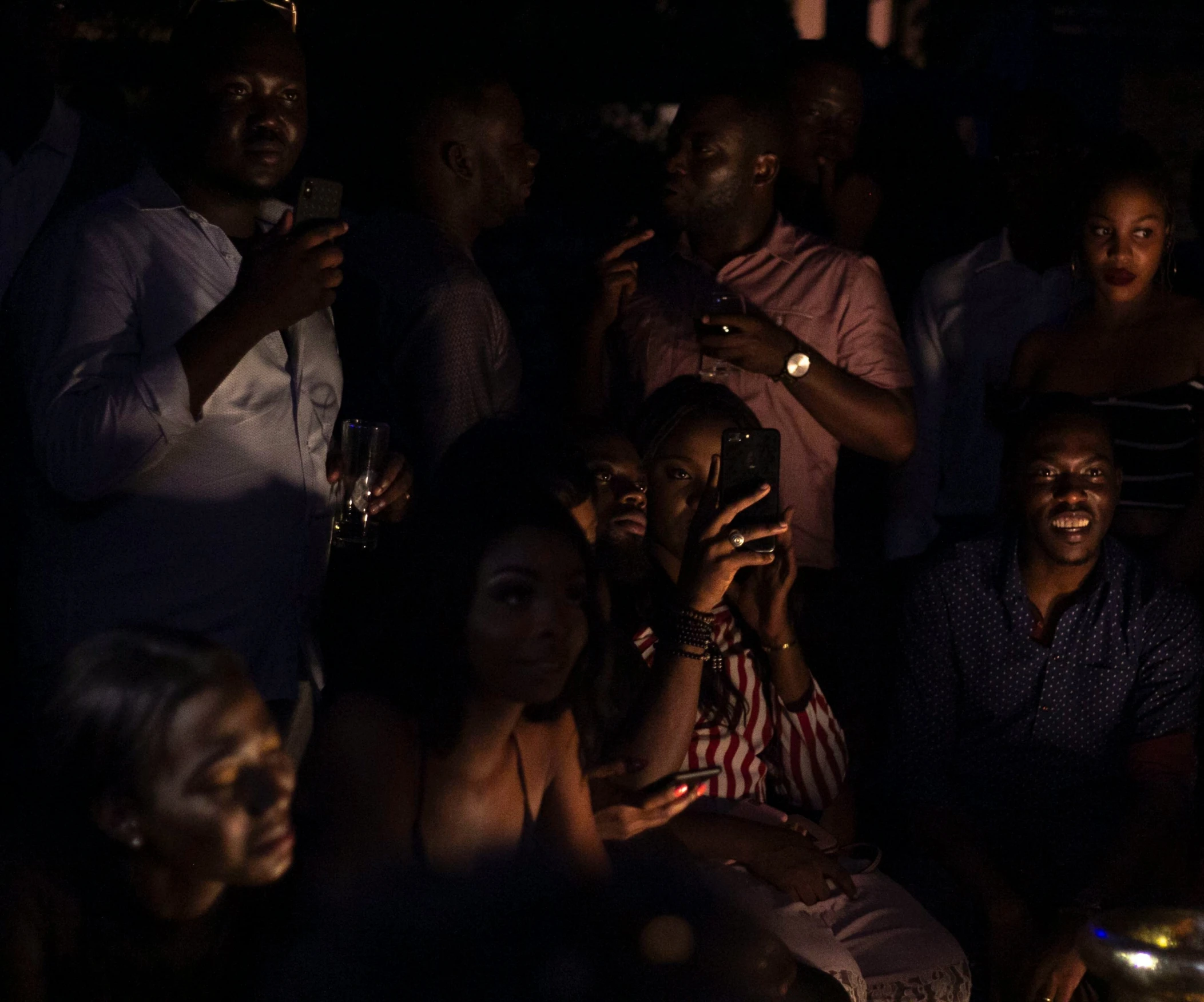 several people with phones sitting and smiling at night