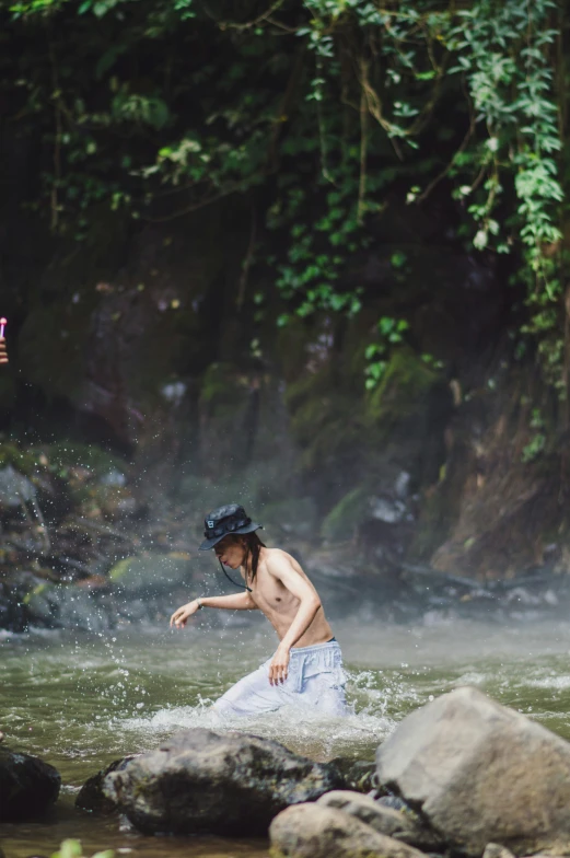 a boy jumping into a stream in the mountains