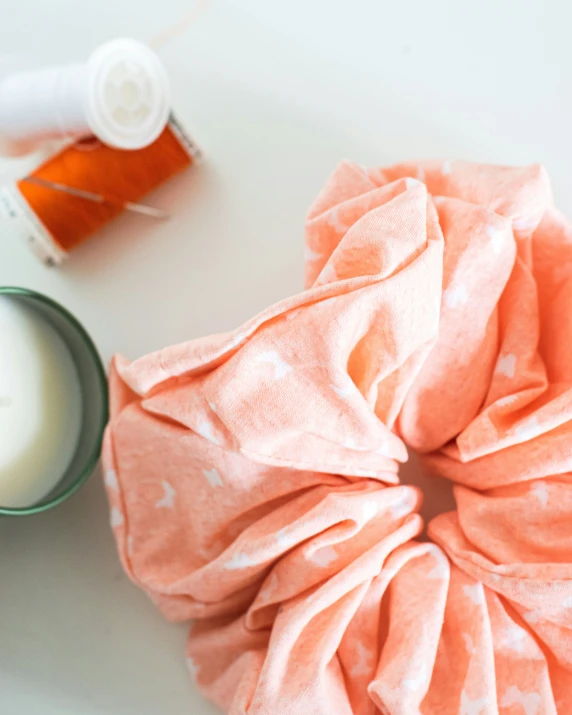 a hair scrunchie sitting on top of a table next to a container of cream