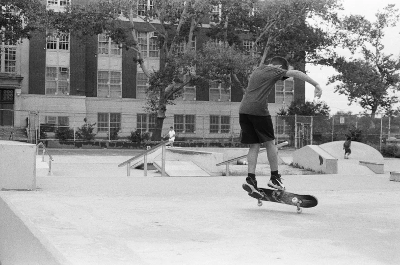 black and white pograph of young man skateboarding in courtyard