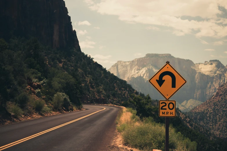 a yellow road sign on the side of a mountain road