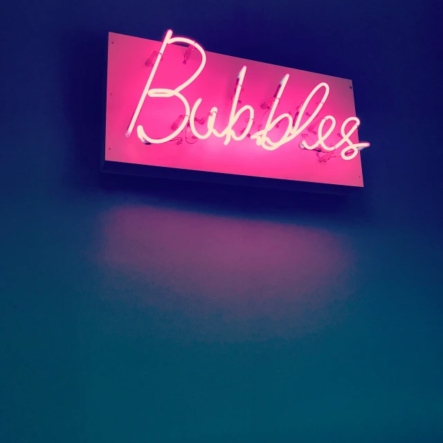 a pink bubble light sign hanging from the wall