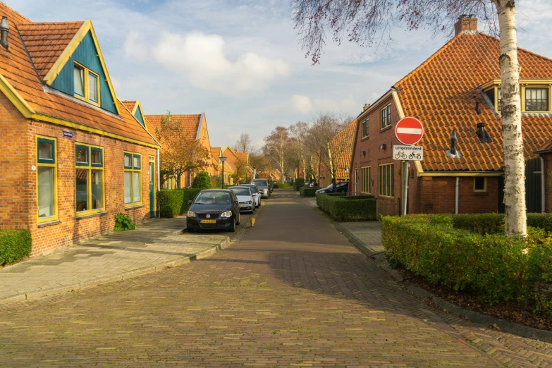 a cobblestone street with parked cars and brick buildings