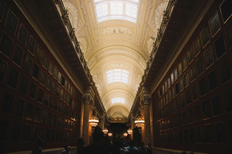 an indoor building with lights, bookshelves and people walking