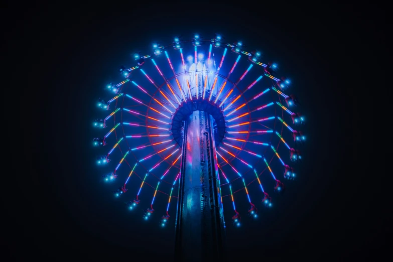 a ferris wheel spins at night with bright lights