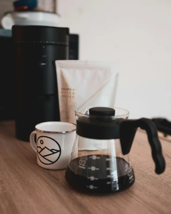 there is a cup sitting on the table beside a coffee maker