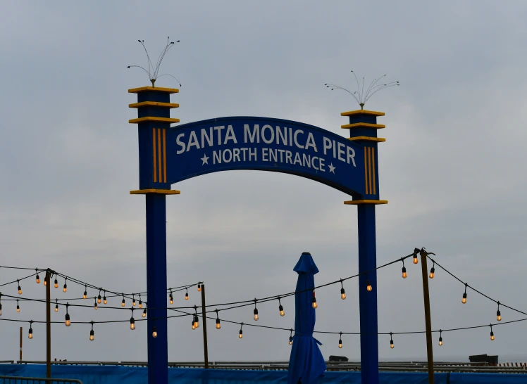 large blue sign for santa monica pier with christmas lights