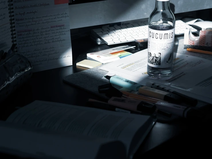 a bottle of wine sitting next to a keyboard and papers