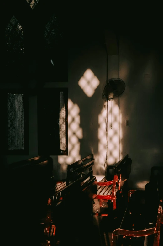 shadows form on the wall of a classroom room with several wooden benches in it