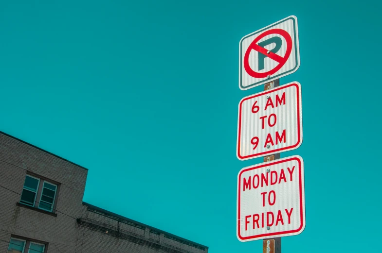 three traffic signs on a pole near a building