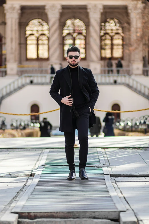 a man wearing a black coat stands in front of a building