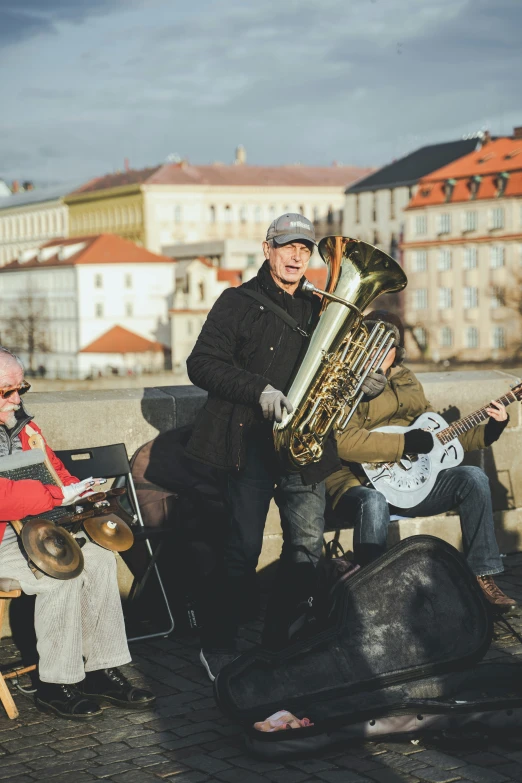 a musician with a golden french horn and a man with white guitar