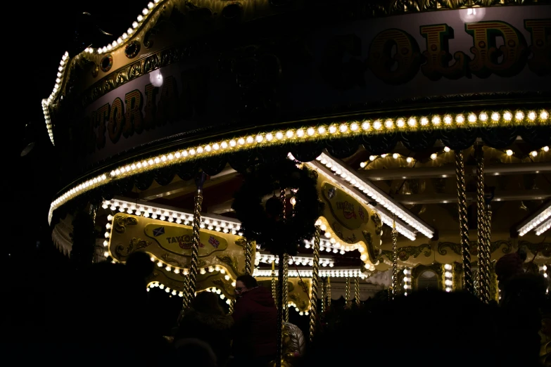 people are standing by an illuminated merry go round