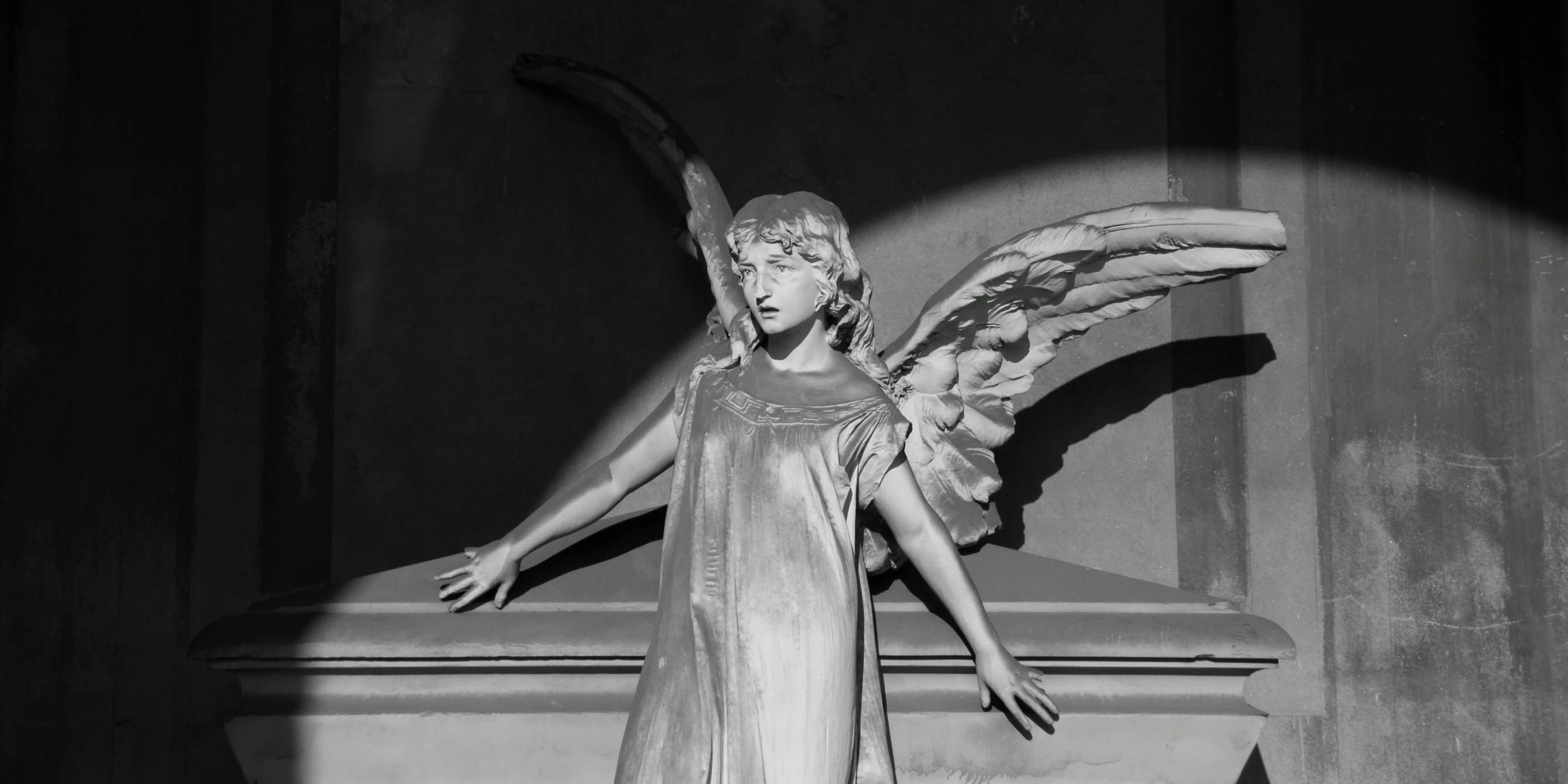 a black and white image of a statue with a winged figure