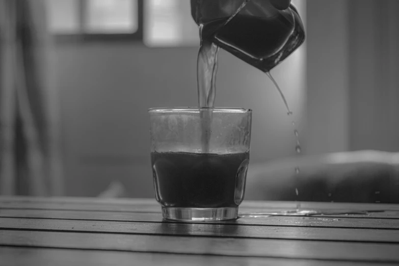 a person pouring tea into a glass cup