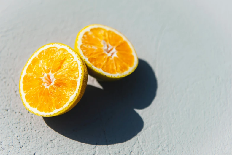 two oranges sliced in half and sitting on the ground