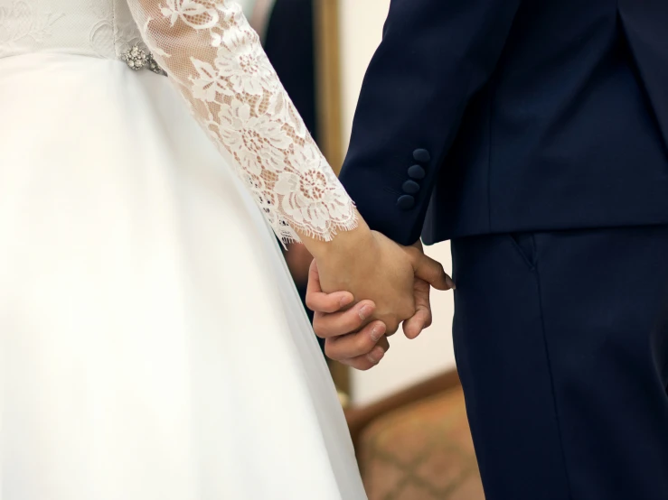 a close up of a bride and groom holding hands