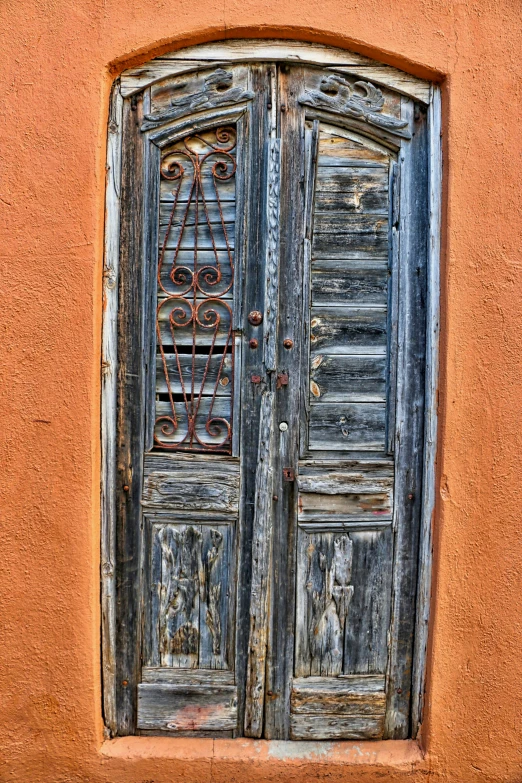 a very old door in an old stucco wall