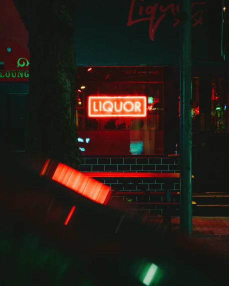 neon lights shining on the dark outside of a liquor store